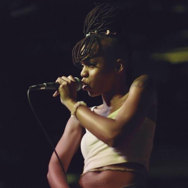 Dynasty rapping into a microphone in low stage light