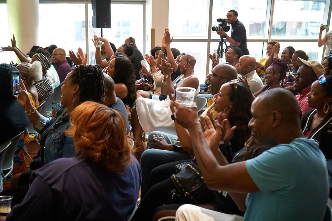 Audience members clapping and raising hands during a Dynasty event