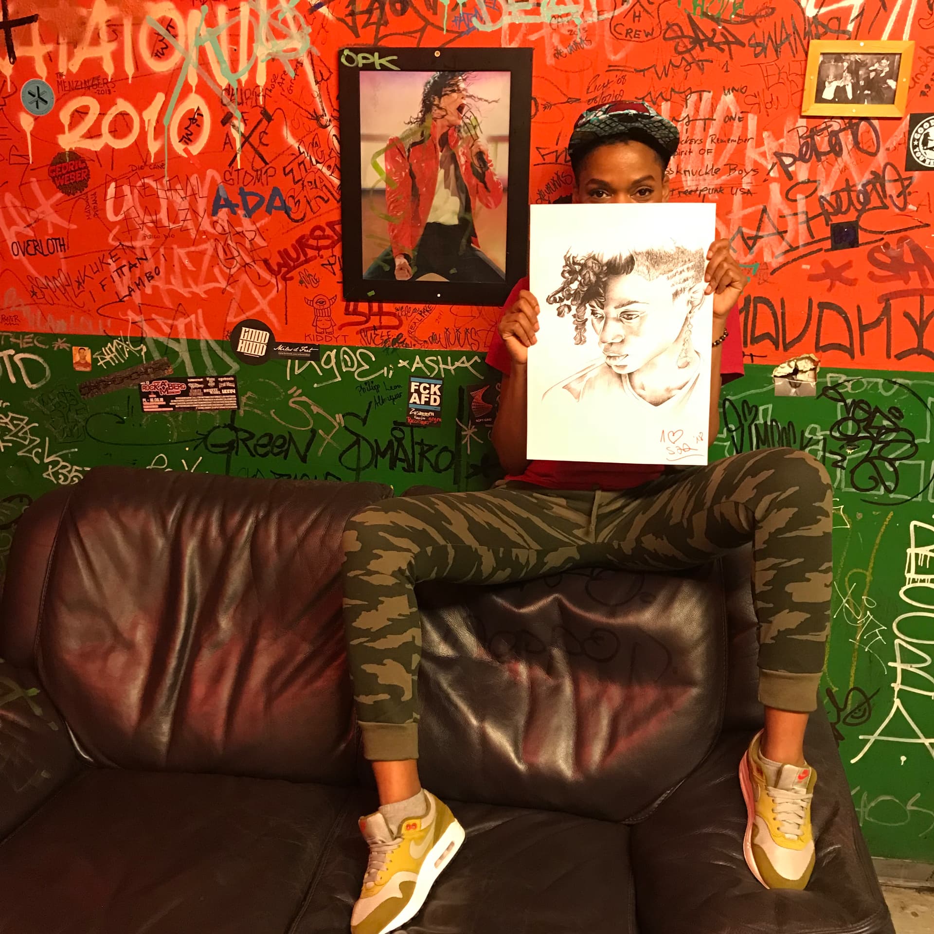Dynasty holding a hand-drawn portrait up to her face backstage