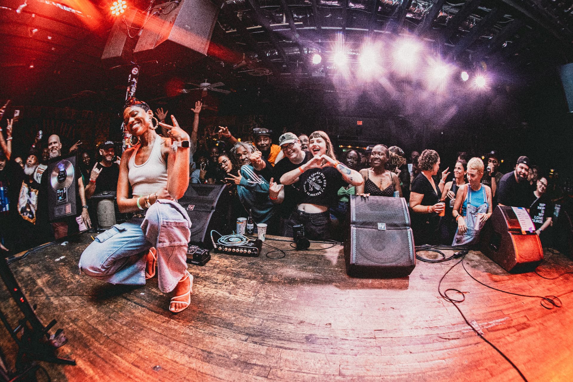 Dynasty kneeling at the edge of the stage with a celebrating audience
